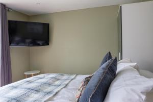 a bedroom with a bed with a flat screen tv on the wall at Dickens Suite- 15min close to Gatwick in Crawley