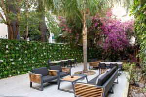 a patio with chairs and tables and a tree with pink flowers at Hotel Saint Georges in Nice