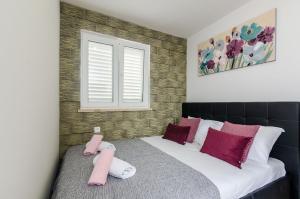 Un dormitorio con una cama con almohadas rosas y una ventana en Apartments Monica, en Dubrovnik