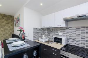 a kitchen with white cabinets and a sink and a microwave at Apartments Monica in Dubrovnik