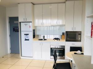 a kitchen with a refrigerator, stove, sink and microwave at Hiigh Apartments in Melbourne