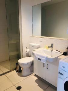a white toilet sitting next to a sink in a bathroom at Hiigh Apartments in Melbourne