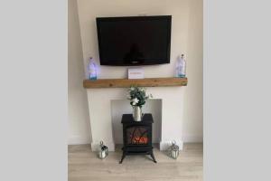 a living room with a fireplace with a tv and a stove at TomaX Garden Cabin Free Parking in Inverness