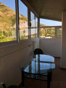 a glass table and a chair in a room with windows at Kuća Radović in Budva