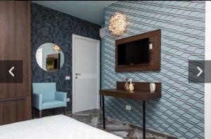 a bedroom with a bed and a tv and a chair at 4Essences Boutique Rooms in Maratea