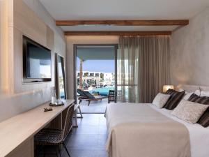 a hotel room with a bed and a desk and a balcony at Atlantica Dreams Resort in Gennadi +37 photos