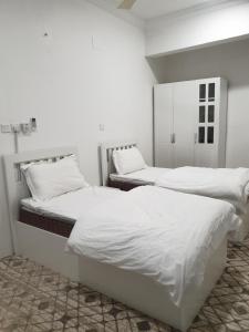 Habitación con 2 camas individuales y paredes blancas. en الحساني بلازا أضم, en Adham