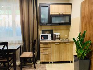 a kitchen with a sink and a microwave and a table at Тетя Соня in Romny