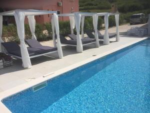 a row of lounge chairs next to a swimming pool at Bara Bay in Metajna