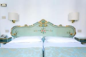 a bed with a blue headboard and two pillows at Hotel Serenissima in Venice
