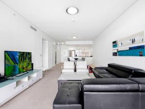 a living room with black leather furniture and a flat screen tv at Beautiful Ocean View High Floor 3 Bedroom Apartment at Sierra Grand in Gold Coast