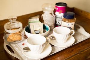 un plateau avec des tasses et des soucoupes sur une table dans l'établissement St Annes Bed and Breakfast, à Painswick