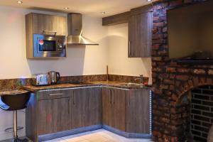 a kitchen with wooden cabinets and a brick fireplace at 19 Rodney Street Apartments in Liverpool