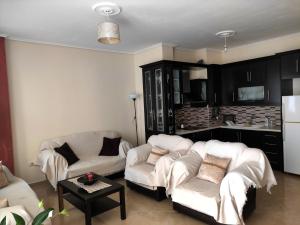 a living room with two white couches and a kitchen at Apartment Angel in Sarandë