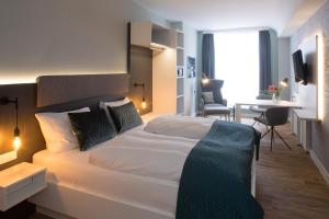 a bedroom with a large white bed and a desk at Weberei Bendix Hotel & Appartements in Dülmen