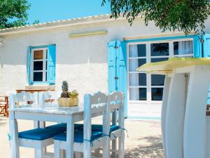 a white table and chairs with blue doors and a house at Klima Paradise in Klíma