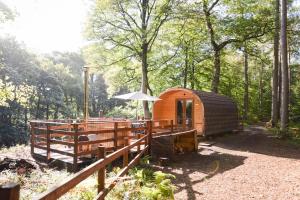 a wooden cabin with an umbrella in the woods at Broomhills Farm River Eco Pods in Carlisle