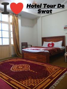 a hotel room with two beds and a red heart rug at Hotel Tour De Swat in Swat