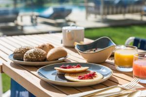 a wooden table with plates of breakfast foods and drinks at Golden Tulip Porto-Vecchio in Porto-Vecchio
