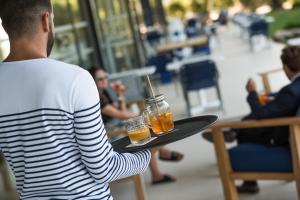 a man holding a tray with two drinks on it at Golden Tulip Porto-Vecchio in Porto-Vecchio