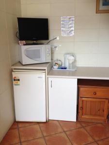 a small kitchen with a microwave and a refrigerator at Sunburst Motel in Gold Coast