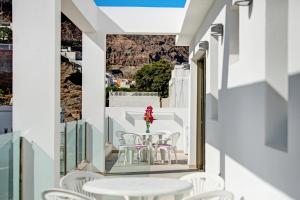 a balcony with white chairs and a table with a vase of flowers at Atico Albamar in Puerto de Mogán