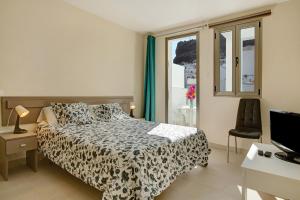a bedroom with a bed and a desk and a television at Atico Albamar in Puerto de Mogán