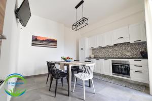 a kitchen with white cabinets and a table and chairs at La Posidonia - Villa Abele in Marsala