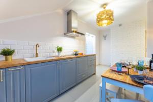 cocina con armarios azules, fregadero y mesa en Apartament Kasztelan II, en Ustrzyki Dolne