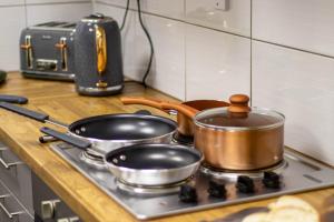 dwa garnki i patelnie na kuchence w kuchni w obiekcie CADeS accommodation w mieście Wolverhampton