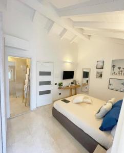 a white bedroom with a large bed and a television at Corso Umberto Rooms in Olbia