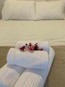 Pousada Cocar Caraíva في كرايفا: منشفة بيضاء عليها ورد فوق السرير