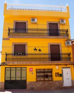 Edificio amarillo con balcón en Vivienda turística María de Padilla, en Montiel