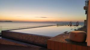 a swimming pool next to the ocean at sunset at Can Salia in San Antonio Bay