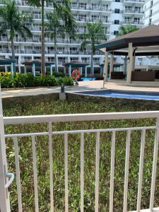 a white fence next to a swimming pool with a building at Kathys Crib at Shell Residences in Manila