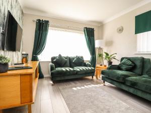 a living room with two green couches and a window at 2 Pine Grove in Preston