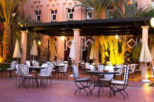 an outdoor patio with tables and chairs and umbrellas at Berbère Palace in Ouarzazate