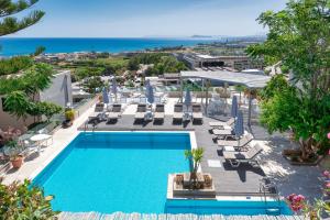 an image of a swimming pool with chairs and the ocean at Aphea Village in Kolymvari