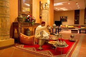 a man sitting in a room with a fireplace at Berbère Palace in Ouarzazate