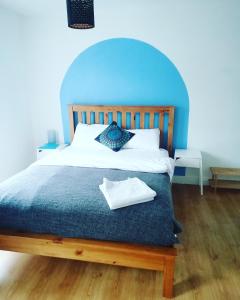 a bedroom with a bed with a blue headboard at Big Yellow Door in Queens Quarter in Belfast