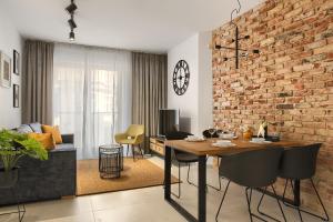 sala de estar con mesa y pared de ladrillo en Elite Apartament IMPERO z Parkingiem en Poznan