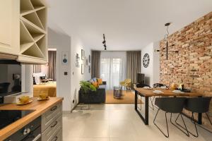 cocina y sala de estar con mesa y pared de ladrillo en Elite Apartament IMPERO z Parkingiem, en Poznan