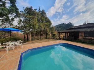 einen Pool im Garten mit Tisch und Sonnenschirm in der Unterkunft Refúgio dos Pássaros in Santo Antônio do Pinhal
