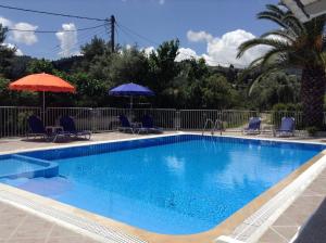 a blue swimming pool with chairs and umbrellas at Polyxenis Rooms in Lygia