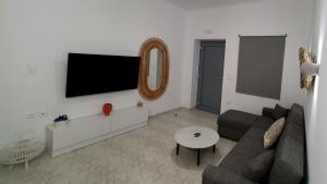 a living room with a couch and a tv on a wall at Alexandra's Boutique House in Triovasálos