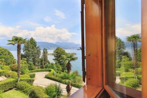 a window with a view of a lake and palm trees at Appartamento Albert - Stresa in Stresa