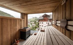 a wooden balcony with benches and a large window at Stoa - Elegant & Romantic Guest House - "Adults only" in San Vigilio Di Marebbe