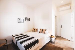 Dormitorio blanco con cama con manta a rayas en A Casa da Cerca, en Almodôvar