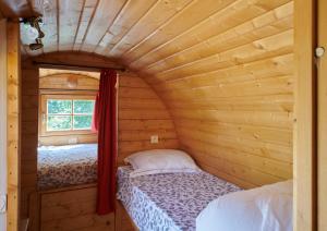 a small bedroom with a bed in a log cabin at Les Tonneaux Bourguignons du carré Saint Pierre in Marey-lès-Fussey