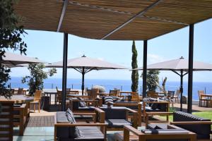 um restaurante com cadeiras, mesas e guarda-sóis em Madeira Regency Cliff - Adults Only no Funchal